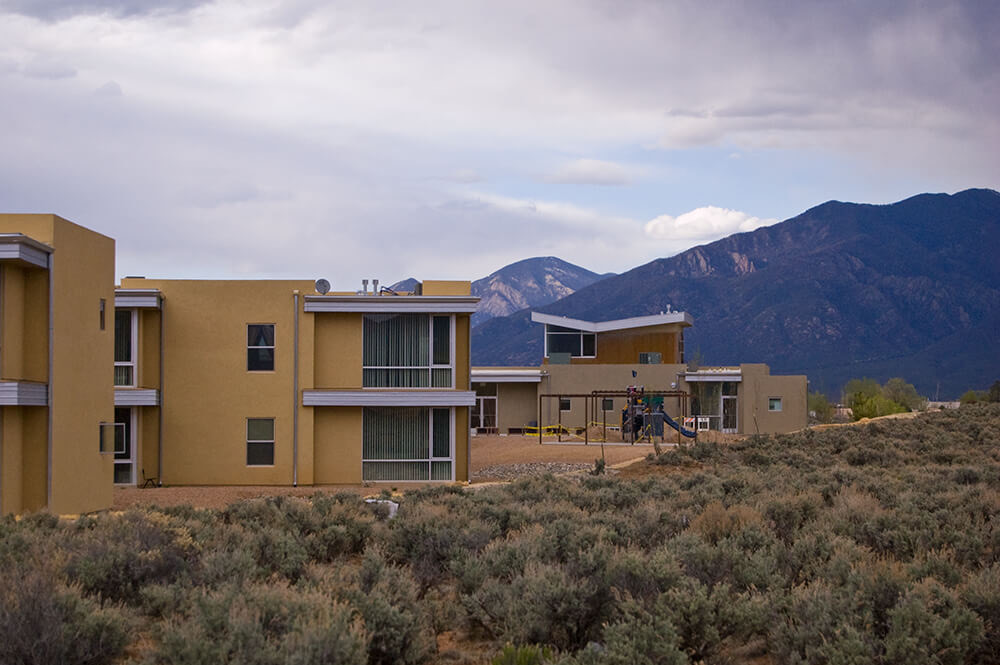 El Cerrito apartment homes above the sagebrush in Taos, NM, with the play area between buildings and Taos Mountain beyond